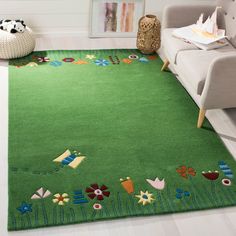 a green area rug with flowers and birds on it in a living room next to a couch