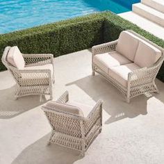 three wicker furniture sitting on top of a patio next to a swimming pool