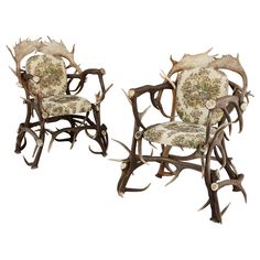 two chairs with antlers on them sitting side by side in front of each other