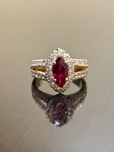 "DeKara Designs Collection Metal- 18K Yellow Gold, .750. Stones- Marquise Ruby Center Beautiful Red Color 1.07 Carats. 16 Round Diamonds F-G Color VS2 Clarity, 1.15 Carats. This is a halo setting with a magnificent marquise ruby set in the center surrounded by 48 round diamonds in a \"U\" pave setting, and features a split shank. The marquise ruby is 1.07 carat with an beautiful hue of red in color. Rubies are the rarest of fine gemstone! The side stones are all F-G in color and VS2-SI1 in clari Marquise Cluster Ring With Accent Stones For Wedding, Luxury Marquise Ruby Gold Jewelry, Exquisite Gold Marquise Cut Ring, Gold Marquise Wedding Ring With Accent Stones, Luxury Ruby Birthstone Ring For Wedding, Exquisite Gold Ring With Marquise Cut, Gold Marquise Ring With Accent Stones, Gold Marquise Birthstone Ring With Accent Stones, Red Marquise Ring With Diamond Accents