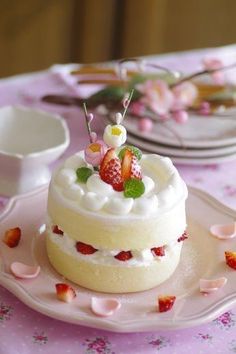 there is a small cake on the table with strawberries and flowers all around it