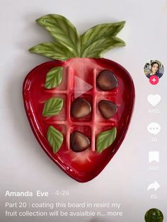 a red strawberry shaped chocolate mold sitting on top of a white table next to a green leaf