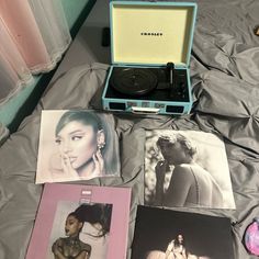 an open record player sitting on top of a bed next to pictures and other items