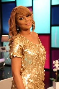 a woman in a gold sequin dress standing next to a vase with flowers on it