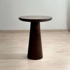 a wooden table sitting on top of a hard wood floor next to a white wall