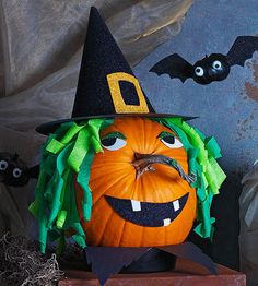 a pumpkin decorated with green hair and a witch hat