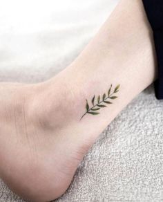 a woman's foot with a small green leaf tattoo on the left side of her leg