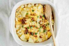 a casserole dish with potatoes and green onions in it on a white cloth