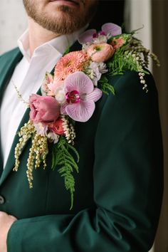 a man in a green suit with flowers on his lapel