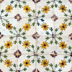 an artistic tile design with yellow flowers and green leaves on white tiles, which are hand painted in bright colors