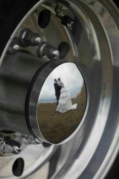 a bride and groom are reflected in the spokes of a car wheel