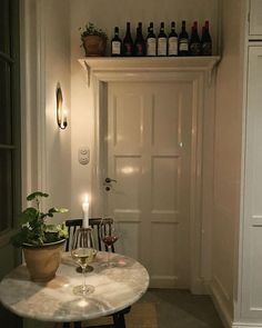 a table with two wine glasses on it next to a white door and some bottles