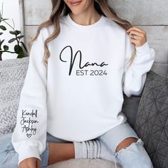 Celebrate the special bond between a Nana and her grandchildren with our unique Personalized Nana sweatshirt. This sweatshirt can be personalized with the grandmother's nickname (Gigi, Mimi, Nana, Grandma, Abuela, Lolli, etc.), her special EST date, and the name of her grandchildren making it an extra special gift that she will remember forever.  Enter the name you would like (see picture #6 for options), the year, and the name(s) you would like printed in the personalization box and we will tak White Relaxed Fit Sweatshirt For Birthday, White Long Sleeve Sweater With Name Print, Personalized White Sweatshirt For Family Matching, Personalized White Tops For Winter, Personalized White Long Sleeve Tops, Personalized Long Sleeve White Tops, Family Matching White Long Sleeve Sweatshirt, White Long Sleeve Family Matching Sweatshirt, White Long Sleeve Sweatshirt For Family Matching