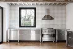 an empty kitchen with stainless steel appliances and wood flooring