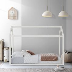 a white bed sitting in a bedroom next to two hanging light fixtures on the wall