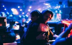 two women hugging each other in a dark room with neon lights on the walls and floor