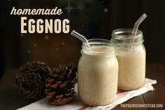 two mason jars filled with homemade eggnog next to a pine cone