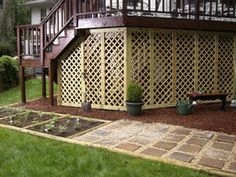 a wooden deck with potted plants in the middle and stairs to the second floor