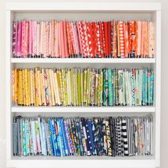 a book shelf filled with lots of different colored fabrics