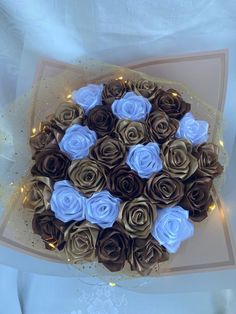 a bouquet of blue and brown paper roses on a card board with lights in the background