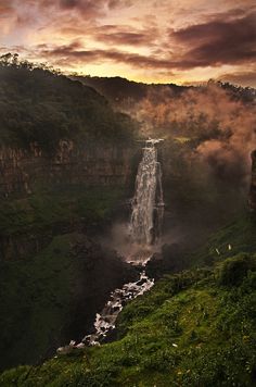 a waterfall in the middle of a lush green valley