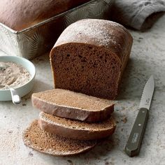 a loaf of bread sitting on top of a counter next to a knife and bowl