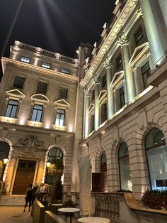 the building is lit up at night with lights on it's windows and balconies