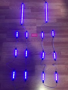 several blue lights on a wooden floor with wires attached to them and some cords connected to the ground