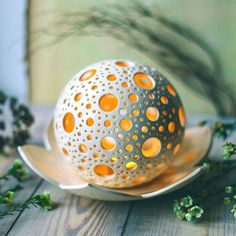 an egg sitting on top of a saucer next to some green plants and flowers