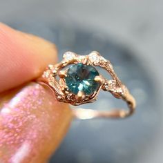 a close up of a person's hand holding a ring with a blue stone in it