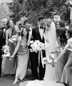 a group of people standing next to each other in front of trees and flowers on the grass