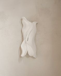 a white sculpture is hanging on the wall