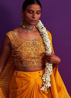 Features a mustard yellow bandhani cape with zari work on sleeves teamed with a heavily embroidered crop top. Completed with a draped lehenga. Composition : Silk Care: Dry Clean Only and Vacuum Storage This product can be customised for sleeves, length of blouse and neckline Delivery : 4-6 weeks as the product is hand crafted. For more information and sizes please contact fabiliciousfashion@gmail.com or visit our Copenhagen studio.About the Designer : Pink City by Sarika, established in 2014, is a young and modern brand that offers modern indo western silhouettes with old world sophistication. With a meticulous eye for detail and an unwavering passion for creating beautifully made clothes, Pink City by Sarika has become synonymous with Indian indo western wear. The brand's distinct style a Yellow Festive Sets With Cape Sleeves, Festive Yellow Sets With Cape Sleeves, Traditional Dupatta With Cape Sleeves And Pallu, Traditional Sharara With Gota Work And Cape Sleeves, Wedding Dupatta With Gota Work And Cape Sleeves, Navratri Traditional Wear With Dupatta And Cape Sleeves, Traditional Wear With Resham Embroidery And Cape Sleeves, Festive Sets With Gota Work And Cape Sleeves, Bollywood Style Sharara With Cape Sleeves For Navratri