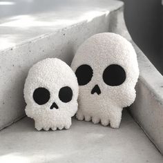 two fake skulls with black eyes sitting on concrete