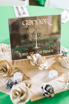 a table topped with lots of paper flowers next to a sign that says lord of the rings