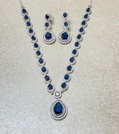 Sapphire Jewelry Set features a stunning blue diamond necklace adorned with cubic zirconia. Inspired by Sabyasachi, this contemporary statement piece is perfect for weddings. Its elegant design makes it a beautiful and memorable gift for her on her special day. *𝐏𝐑𝐎𝐃𝐔𝐂𝐓 𝐃𝐄𝐓𝐀𝐈𝐋* * 𝐌𝐚𝐭𝐞𝐫𝐢𝐚𝐥: Brass * 𝐏𝐥𝐚𝐭𝐢𝐧𝐠: White Rhodium Plated * 𝐒𝐭𝐨𝐧𝐞: AAA-quality CZ Diamond & Sapphire. *𝐃𝐈𝐌𝐄𝐍𝐒𝐈𝐎𝐍𝐒* *𝐍𝐞𝐜𝐤𝐥𝐚𝐜𝐞* * 𝐖𝐞𝐢𝐠𝐡𝐭: 34 gm * 𝐃𝐫𝐨𝐩 𝐋𝐞𝐧𝐠𝐭𝐡: 6.7 c Blue Diamond Necklace For Formal Occasions, Luxury Blue Diamond Necklace For Formal Occasions, Luxury Blue Diamond Necklace, Elegant Sapphire Bridal Necklace For Formal Occasions, Blue Luxury Diamond Necklace For Anniversary, Luxury Blue Diamond Necklace For Anniversary, Elegant Sapphire Necklace With Hand Set Details, Formal Blue Diamond Gemstone Necklace, Formal Blue Gemstone Diamond Necklace