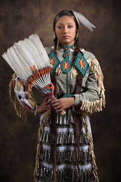 a native american woman holding a fan in her hands