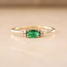 Introducing our Dainty Emerald Ring, a lovely choice for May birthdays or special moments. This minimalist gold ring features a lab-created emerald gemstone in an elegant oval cut. It's a delicate and charming option for an engagement or as a birthstone ring. The small emerald stone is accented with diamonds, adding a touch of sparkle. Celebrate love and life with this exquisite, understated gem. Key Features: * Gemstone: Chatam Lab Created Emerald Stone * Gemstone: Measurements: 1 Piece | Oval Cut 0.30ct * Side Gemstones: 100% Natural Diamonds * Side Gemstones Measurements: 6 Pieces | Round Cut 0.03ct * Material: High-Quality Solid Gold 14k ------CUSTOMIZATION------ ♥ Feel free to contact me for any other customization to your preferences. How to order: * Ordering is easy! Just use the Me Minimalist Gold Ring, Diamond Ring Gold, Emerald And Diamond Ring, Lab Created Emerald, Ring Emerald, Emerald Stone, Emerald Jewelry, Emerald Gemstone, Lovely Jewellery