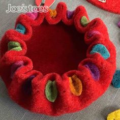 a close up of a red felt ring on a table with other items around it