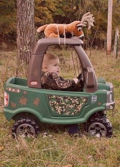 a little boy driving a toy truck with a cat on top