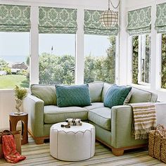 a living room filled with furniture and windows covered in shades of green, white and blue