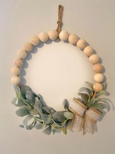 a wreath made out of wood beads and greenery hangs on the wall with a ribbon