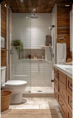 a white toilet sitting in a bathroom next to a walk in shower and wooden cabinets