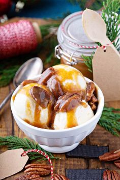 a bowl filled with ice cream covered in caramel and pecans next to christmas decorations