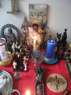 a table topped with figurines and candles on top of a red cloth covered table