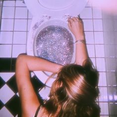 a woman sitting in front of a white toilet