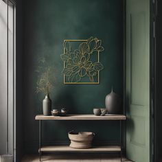 a table with vases and flowers on it in front of a green painted wall