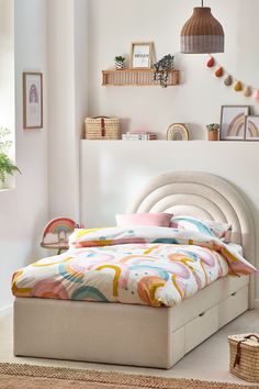 a bed sitting in a bedroom next to a wall with pictures on it and a basket