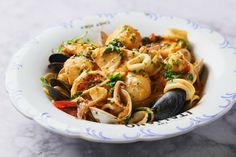 a bowl filled with pasta and mussels on top of a marble countertop