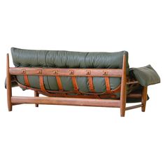 a wooden couch with green cushions and leather straps on the armrests, against a white background